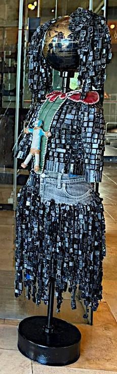 Maurice Mbikayi sculpture: Girl with a Leather Toy 2, installed, a figure with a globe head holding a small doll