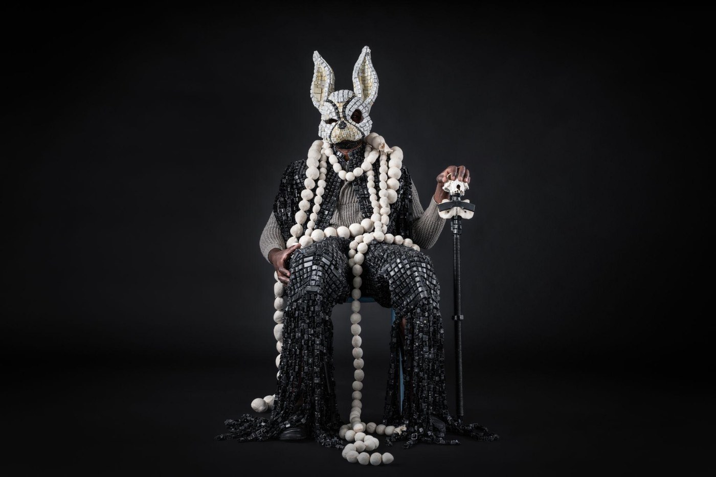 Maurice Mbikayi work: Mask of Heterotopia 1, a seated figure in a rabbit mask and robe made from keyboard keys, with cast-bead necklaces